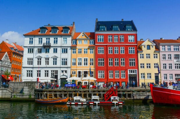 Colorful buildings along Copenhagen canal with boats and people enjoying the waterfront