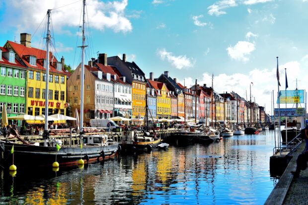 Colorful historic buildings along Copenhagen canal reflecting in the water with boats docked alongside