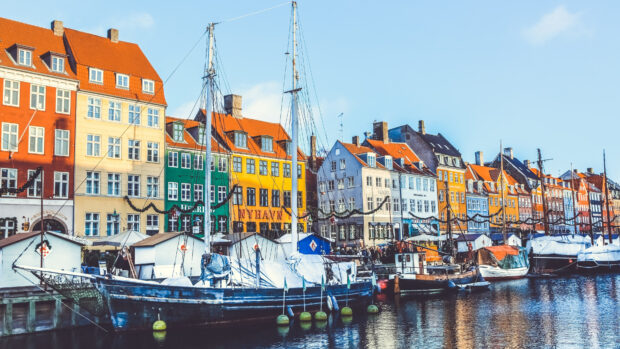 Colorful buildings along the canal in Copenhagen with boats docked under a clear sky