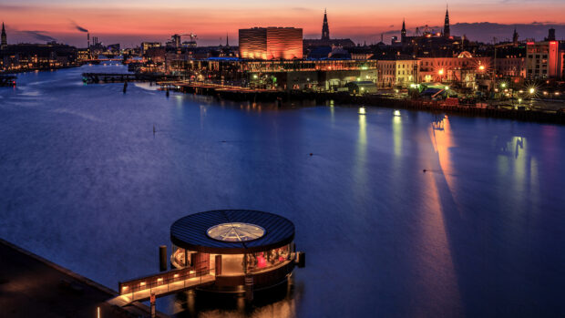 Night view of Copenhagen city with river and illuminated buildings at sunset