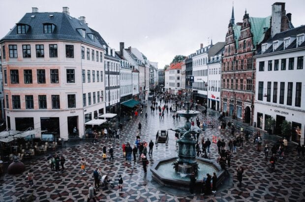 A busy city square with historic buildings and a fountain in Copenhagen