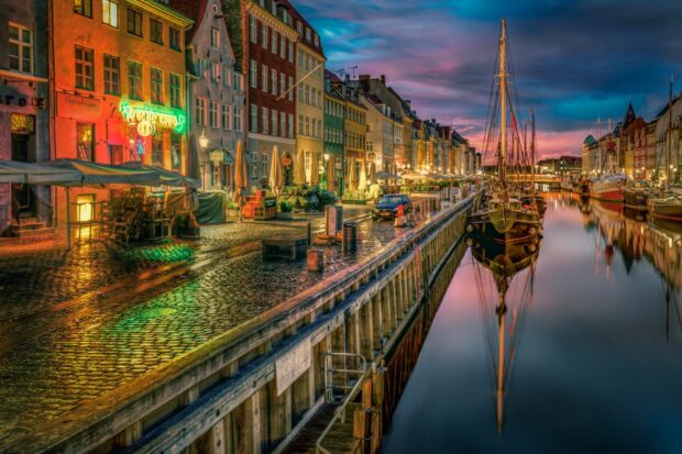 Colorful buildings along the Copenhagen canal at sunset with boats and cobblestone streets