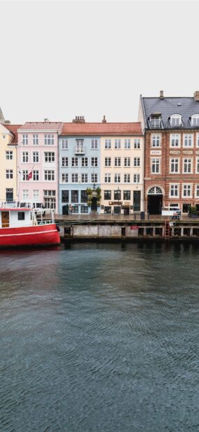 Colorful Copenhagen city buildings along the waterfront with a red boat in the water