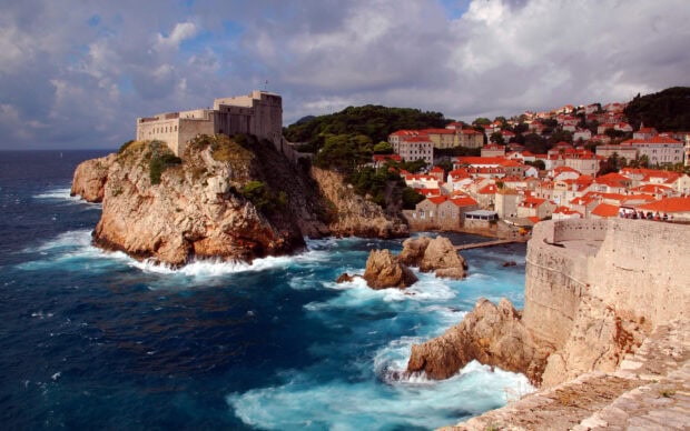 Historic fort on rocky coastline overlooking the Croatian town and Adriatic Sea with red rooftops