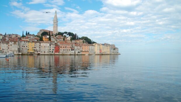Historic townscape of Croatia with church tower reflected on calm sea water