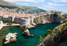 Ancient Croatian coastal fortress and town with clear blue sea and rocky cliffs viewed from hillside