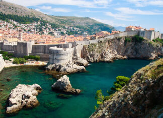 Ancient Croatian coastal fortress and town with clear blue sea and rocky cliffs viewed from hillside