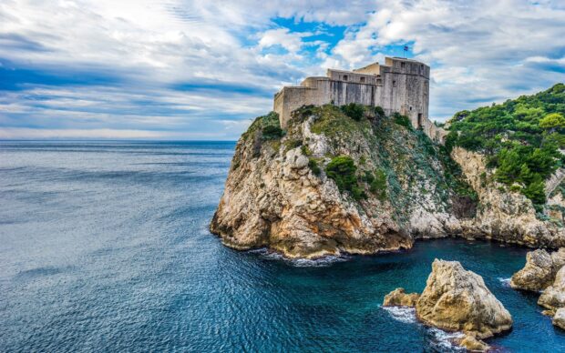 Ancient fortress on rocky coast of Croatia surrounded by blue sea and green vegetation