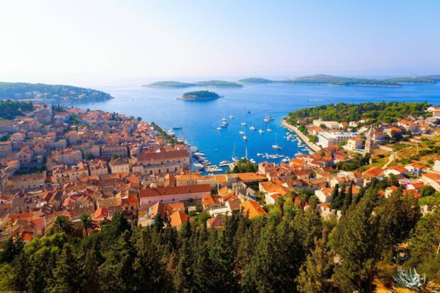 A panoramic view of a Croatian coastal town with islands and sailboats in the blue sea