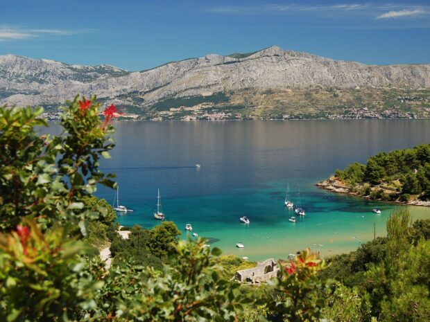 Clear sea with boats near Croatia coastline and mountains in the background