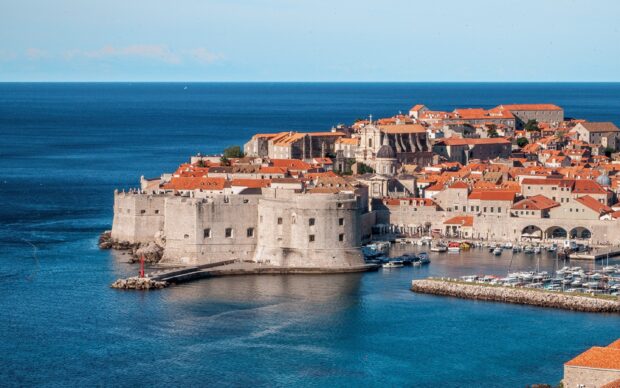 Historic Croatian coastal city with red rooftops and ancient stone walls near the blue sea