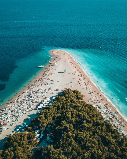A stunning aerial view of Croatia beach with turquoise water and pine trees along the coast