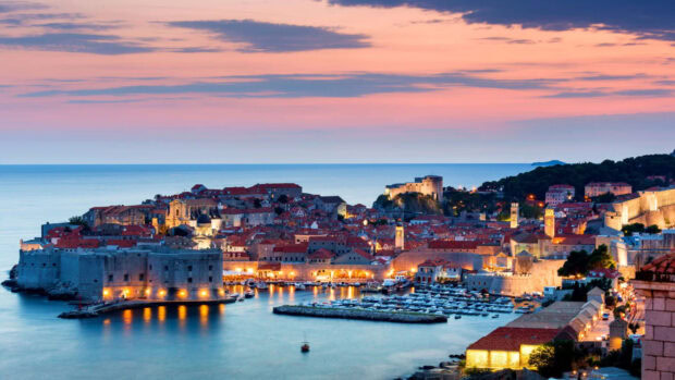 A stunning view of Croatia coastal cityscape at sunset with lit historic buildings and calm sea