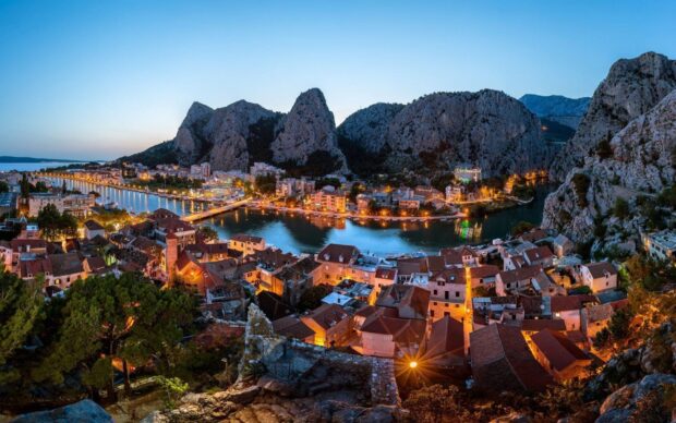 Scenic view of Croatia town and river surrounded by rocky mountains at dusk