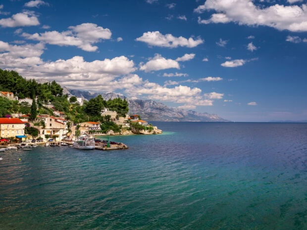 A beautiful coastline of Croatia with mountains and clear blue sea under a partly cloudy sky
