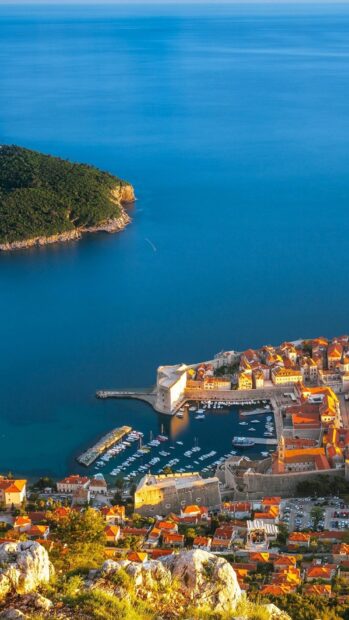 Aerial view of Croatia coastal town with harbor and forested peninsula in clear blue water