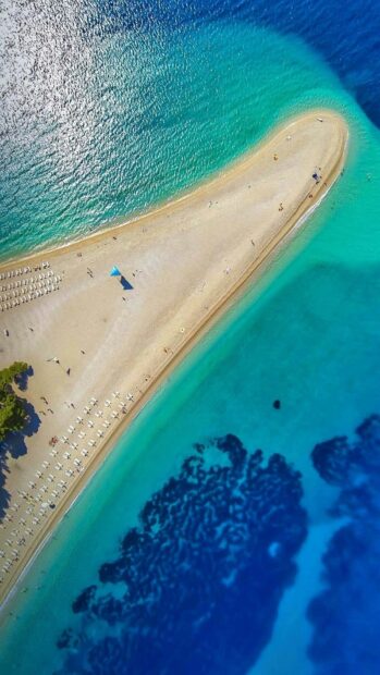 A beautiful coastline in Croatia showing turquoise water and sandy beach from above