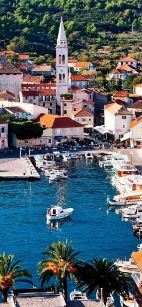 Charming coastal town with boats and historic church tower in Croatia harbor