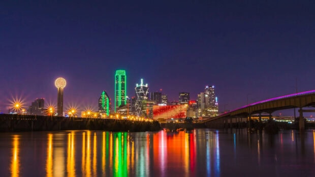 Night skyline with Dallas Texas buildings and colorful lights reflecting on the water