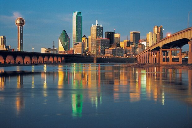 Dallas cityscape with iconic Reunion Tower reflected in water during sunset in Texas