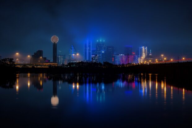 Dallas Texas city skyline with illuminated buildings reflecting on water at night (1)
