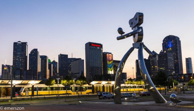 Robot sculpture in Dallas Texas cityscape at sunset with tram and skyscrapers