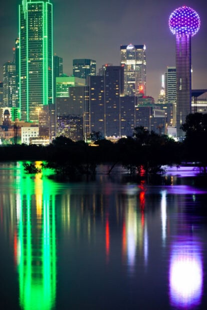 Nighttime Dallas skyline reflections featuring vibrant city lights and iconic Texas architecture