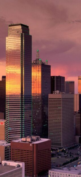 Sunset reflecting on glass buildings in Dallas Texas cityscape at dusk
