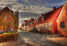 A charming cobblestone street in Denmark with autumn trees and traditional brick houses