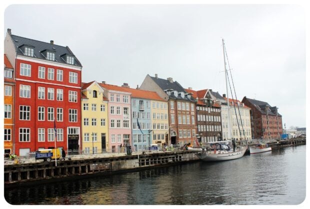 Colorful Copenhagen buildings along the canal in Denmark with boats docked at the pier
