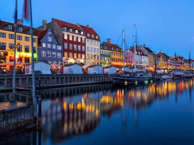 Colorful buildings along the Denmark waterfront reflecting lights on calm water at dusk