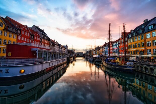 Colorful buildings lining the waterfront in Denmark at sunset reflecting on the calm canal