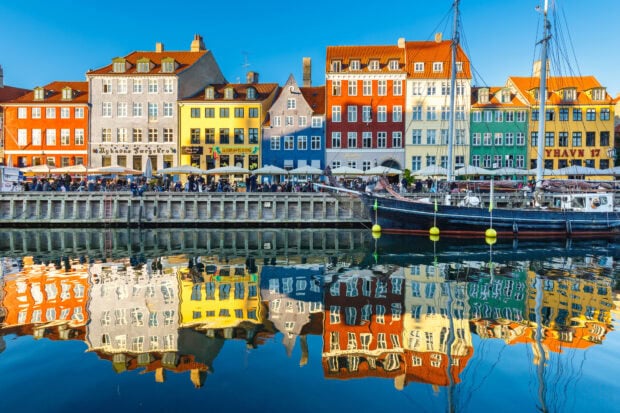 Colorful historic buildings reflecting in the calm water of a canal in Denmark