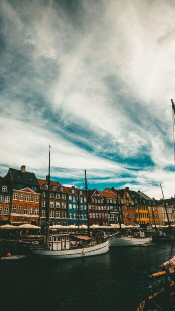 Colorful buildings and boats at a harbor in Denmark under a cloudy sky
