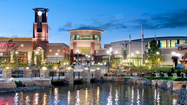 The shopping and entertainment district in Des Moines with illuminated buildings and reflections on water at dusk