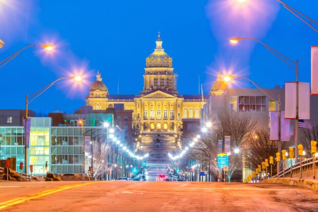 Des Moines city hall illuminated at night with street lights lining the urban road