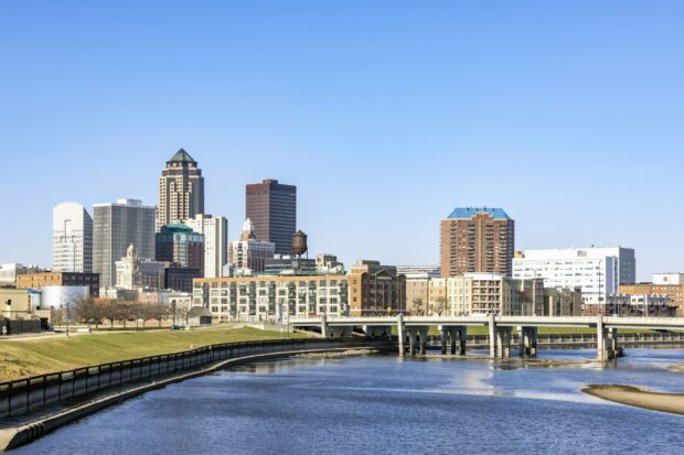 Des Moines city skyline with river and bridge under clear blue sky