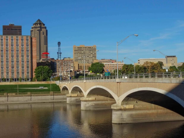 The Des Moines cityscape with a bridge over the river under a clear blue sky