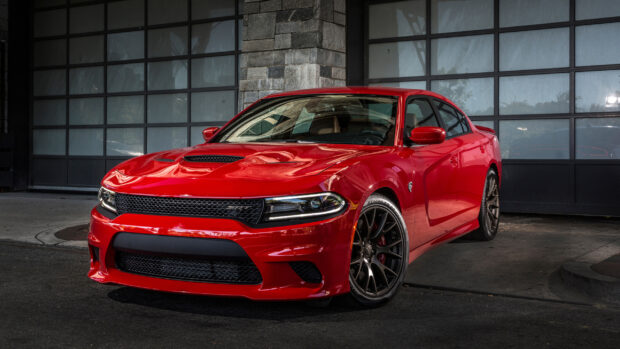 Red Dodge Charger parked in front of a glass garage door showcasing a powerful muscle car design