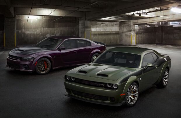 Two Dodge Charger models parked in an industrial garage with one in green and the other in dark purple