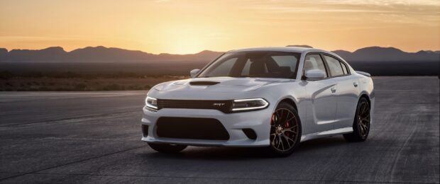 White Dodge Charger parked on road with mountain sunset in the background