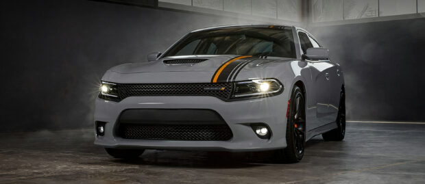 Gray Dodge Charger with racing stripes in a dimly lit garage setting
