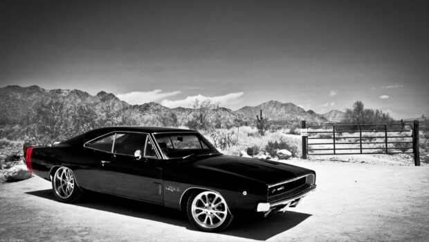 A classic Dodge Charger parked in a desert landscape with mountains in the background
