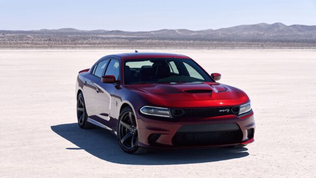Red Dodge Charger car parked on desert terrain under clear sky