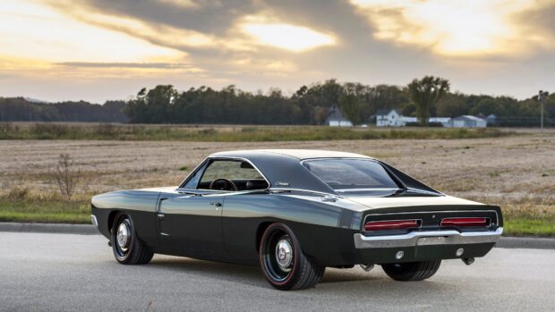 Classic Dodge Charger parked on the road near countryside fields during sunset