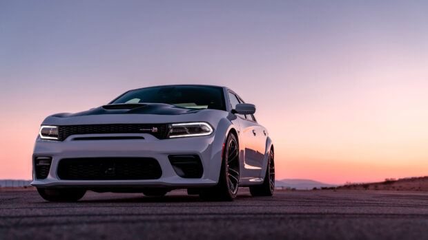 White Dodge Charger on an open road during sunset with a clear sky