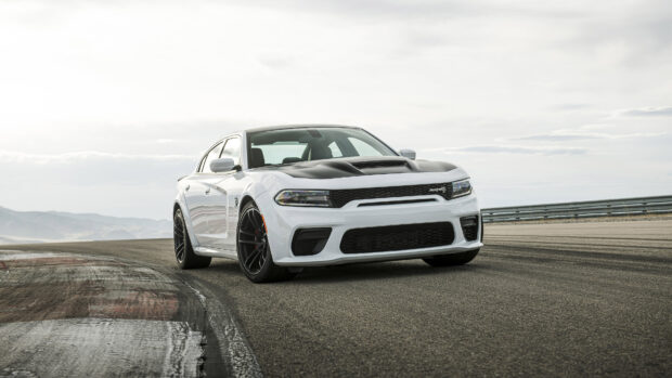 White Dodge Charger parked on a race track under a cloudy sky