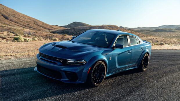 Blue Dodge Charger parked on an asphalt road in a desert landscape with mountains in the background