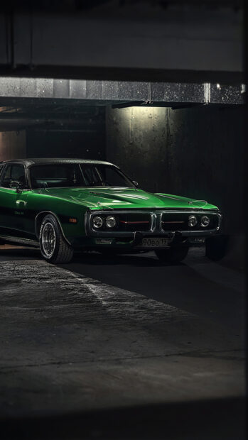 Classic green Dodge Charger parked in a dimly lit garage showing its front side
