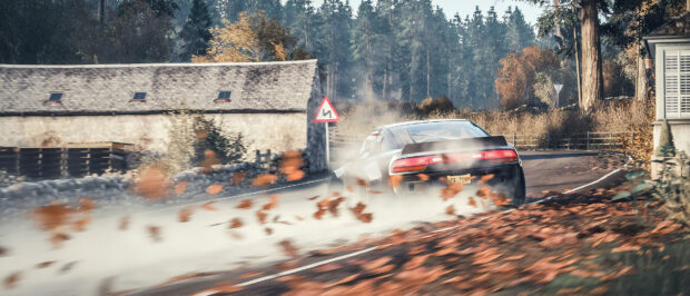 A drifting car is turning sharply on a countryside road surrounded by autumn leaves and trees